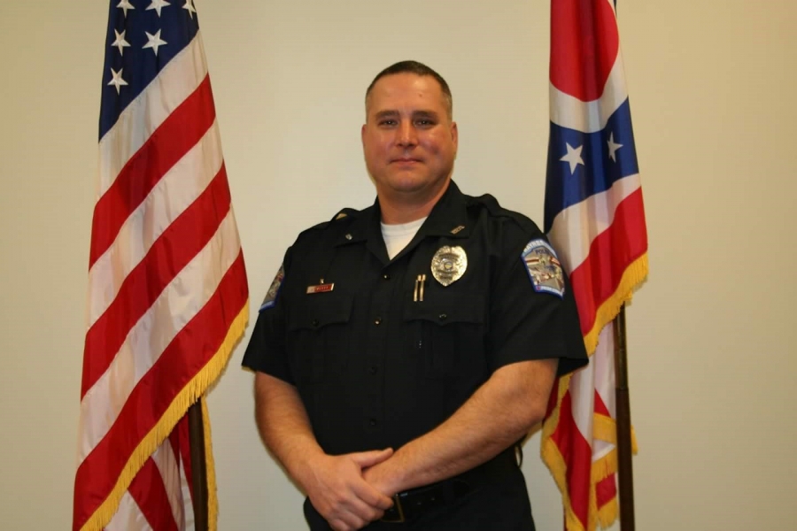 police officer in front of a flag